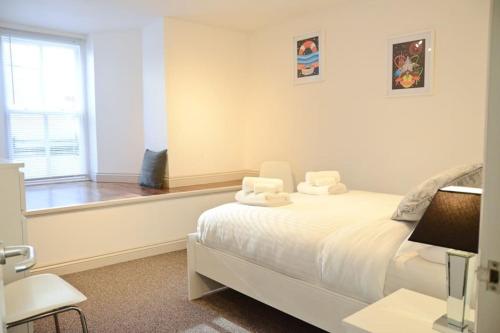 a white bedroom with a bed and a window at Modern 1 bedroom apartment close to Penzance town centre. in Penzance
