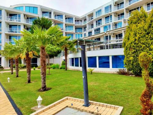 a large apartment building with palm trees and a street light at Design Studio in Atlantis Resort&SPA, Burgas Airport in Burgas City