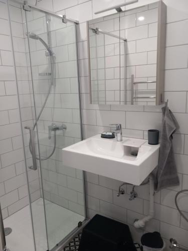 a white bathroom with a sink and a shower at Blue Chill Apartment in Liepāja