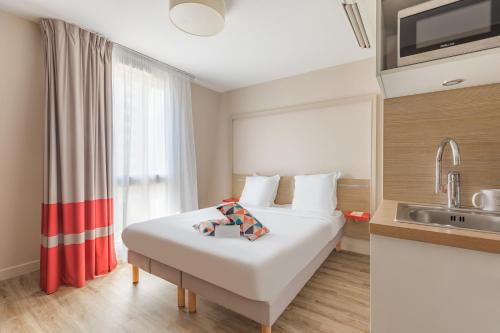 Habitación de hotel con cama y lavabo en Appart'City Confort Bordeaux Chartrons en Burdeos