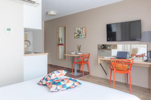 a living room with orange chairs and a kitchen at Appart'City Confort Bordeaux Chartrons in Bordeaux