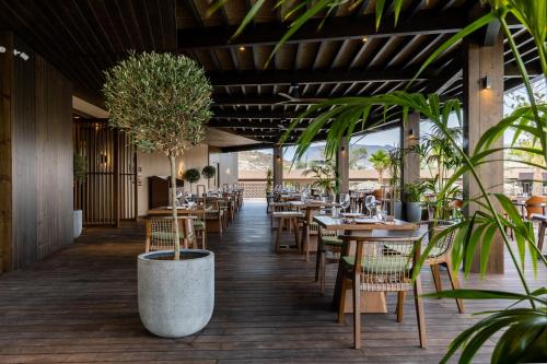 a restaurant with tables and chairs and potted plants at Pnoe Breathing Life - Adults Only in Karteros