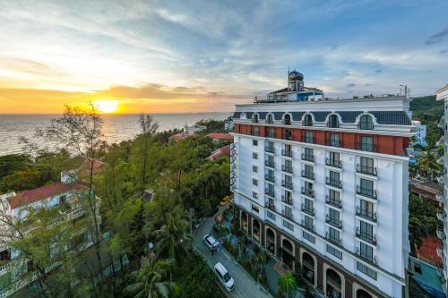 富國的住宿－Aquasun Hotel Phu Quoc，一座白色的大建筑,背面有日落
