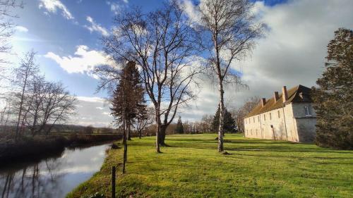 Les Baux的住宿－Abbaye Saint Gilbert，河岸边的一座有树木的建筑