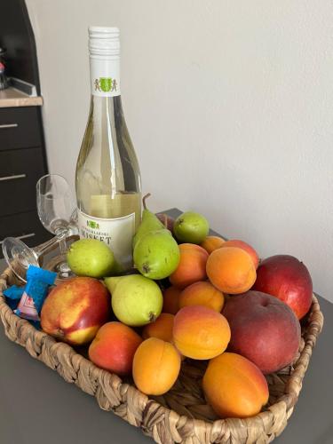 a basket of fruit with a bottle of wine at Лятно студио in Sveti Vlas