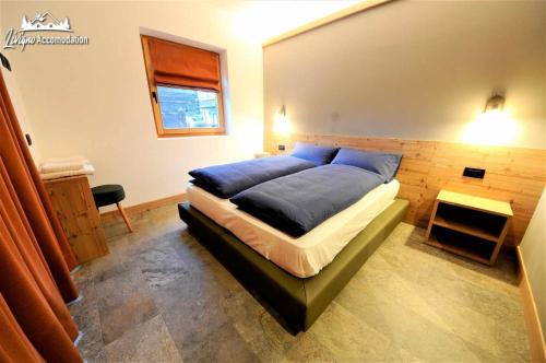 a bedroom with a bed with blue sheets and a window at Abete Rosso Nuovissimo ed in centro a Livigno in Livigno