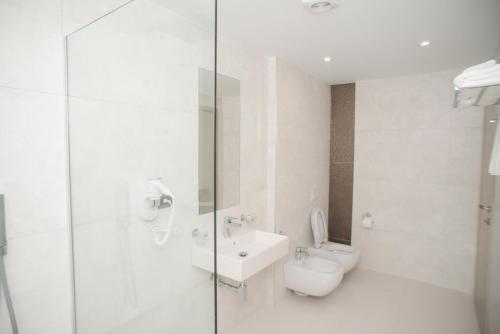 Baño blanco con aseo y lavamanos en Hotel Saranda International, en Sarandë