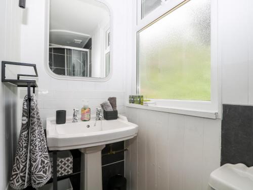 a white bathroom with a sink and a mirror at The Stables Barn in Arundel
