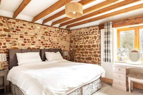 a bedroom with a bed and a brick wall at The Gig House - relaxing countryside spa break in Pentney
