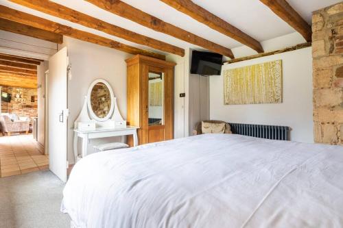 a bedroom with a white bed and a tv at The Gig House - relaxing countryside spa break in Pentney