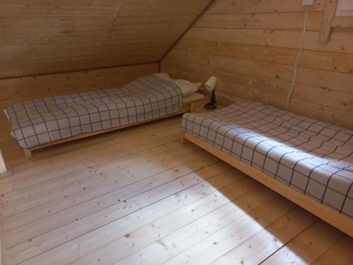 two beds in a room with wooden floors at Bieszczadzka Polana - domki turystyczne/sezonowe in Lutowiska