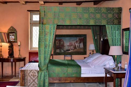 a bedroom with a canopy bed with green curtains at Manoir de Malfarat in Charlieu