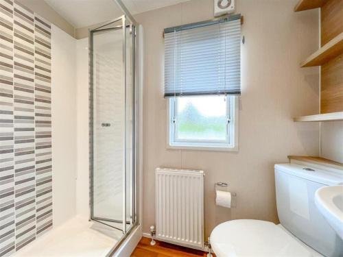 a bathroom with a shower and a toilet and a window at Pottsville Cabin - 2 bed - near Praa Sands Beach in Praa Sands
