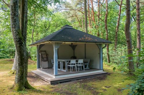 einen Pavillon mit einem Tisch und Stühlen im Wald in der Unterkunft Mistral przy plaży Domki całoroczne in Ustka