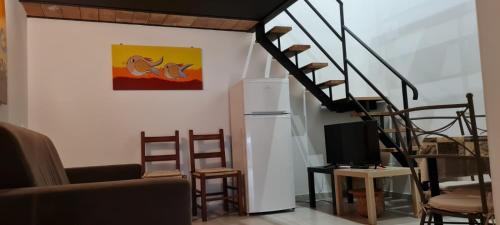 a living room with a staircase with chairs and a tv at House Orlando in Sferracavallo