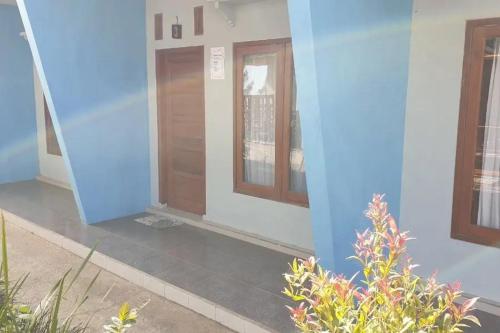 ein Haus mit blauen Wänden und einer Holztür in der Unterkunft Anugrah Bromo Homestay at Desa Wisata Bromo Mitra RedDoorz in Tosari