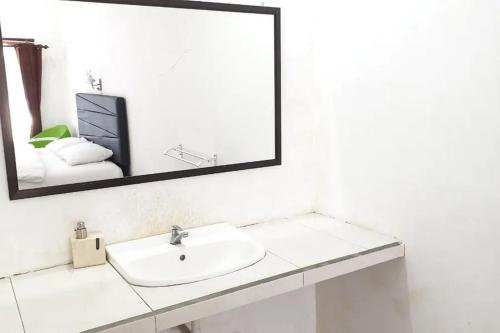 ein weißes Badezimmer mit einem Waschbecken und einem Spiegel in der Unterkunft Anugrah Bromo Homestay at Desa Wisata Bromo Mitra RedDoorz in Tosari