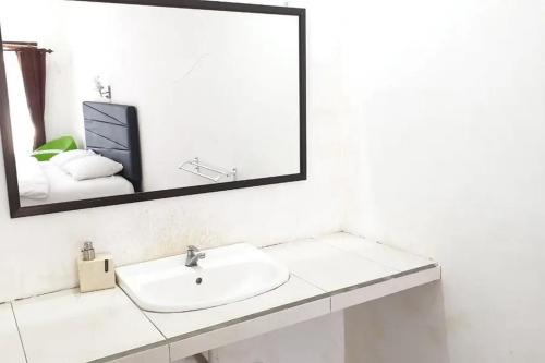 a white bathroom with a sink and a mirror at Anugrah Bromo Homestay at Desa Wisata Bromo Mitra RedDoorz in Tosari