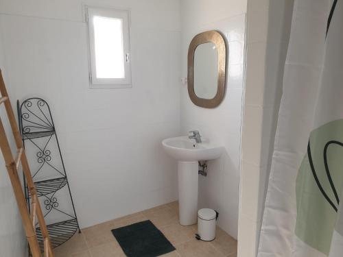 une salle de bain blanche avec un lavabo et un miroir dans l'établissement Gîte de la fontaine, à Buisson