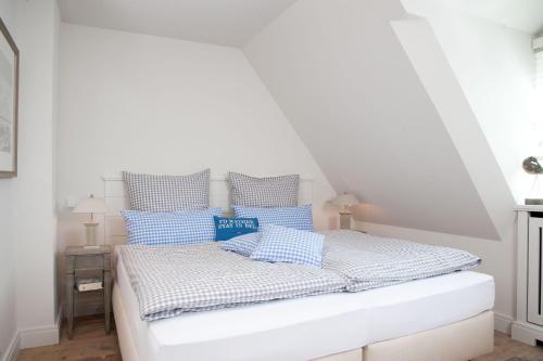 - une chambre blanche avec un lit et des oreillers bleus dans l'établissement Strandhaus-Mylin, à Westerland