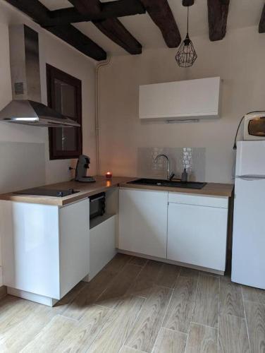 une cuisine avec des armoires blanches et un évier dans l'établissement La Petite Chaume, à Châteauroux