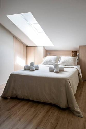 a bedroom with a large white bed with a skylight at LOCA OFIR Duplex - Entre Rio e Mar in Fão