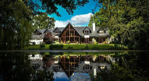 a large house with a pond in front of it at Willowbeck Lodge Boutique Hotel in Carlisle