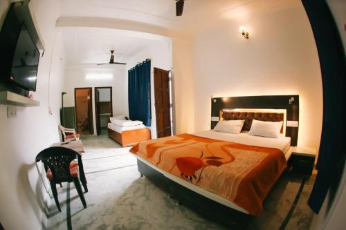 een slaapkamer met een groot bed en een oranje deken bij Maa Vaibhav Laxmi Guest House in Rishīkesh