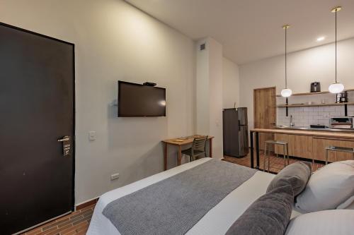 a bedroom with a bed and a tv on the wall at The Somos Flats Laureles in Medellín