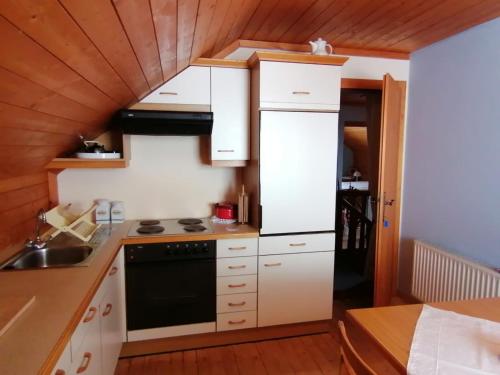 una cocina con armarios blancos y horno negro en Sonnenplatz Appartment Ploninger LANDHAUS en Bad Kleinkirchheim