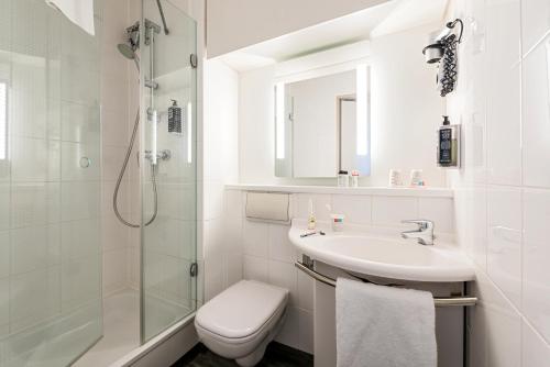 ein weißes Bad mit einem Waschbecken und einer Dusche in der Unterkunft ibis Hotel Regensburg City in Regensburg