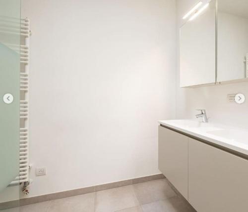 W białej łazience znajduje się umywalka i lustro. w obiekcie Mooi vakantiehuis tussen Breda, Antwerpen, Gent & Hasselt w Antwerpii