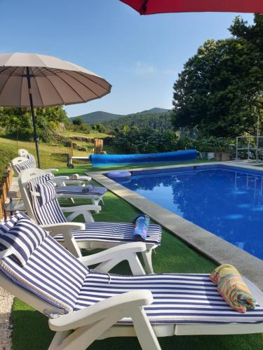 a group of chairs and an umbrella next to a swimming pool at Casa Rural O Bergando in Cotobade