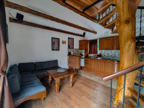 a living room with a couch and a kitchen at Вила Перуле Villa Perule - Handmade cozy wooden villa in the Rhodope mountain in Shumnatitsa