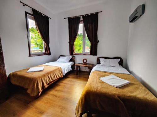 dwa łóżka w pokoju z dwoma oknami w obiekcie Вила Перуле Villa Perule - Handmade cozy wooden villa in the Rhodope mountain w mieście Shumnatitsa