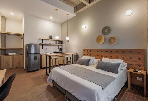 a bedroom with a large bed and a kitchen at The Somos Flats Laureles in Medellín