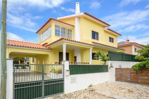 a yellow house with a green fence at CASA AMARELA in Charneca