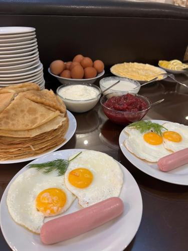 einen Tisch mit Eiern, Würstchen und Pfannkuchen in der Unterkunft Guest House Ritsa in Gagra