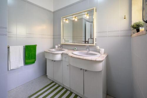 ein weißes Badezimmer mit zwei Waschbecken und einem Spiegel in der Unterkunft CASA AMARELA in Charneca