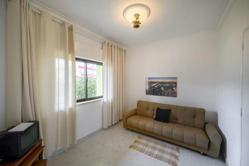 a living room with a couch and a television at CASA AMARELA in Charneca