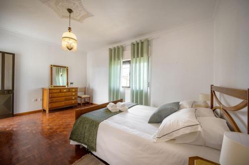 ein Schlafzimmer mit einem großen weißen Bett und einer Kommode in der Unterkunft CASA AMARELA in Charneca
