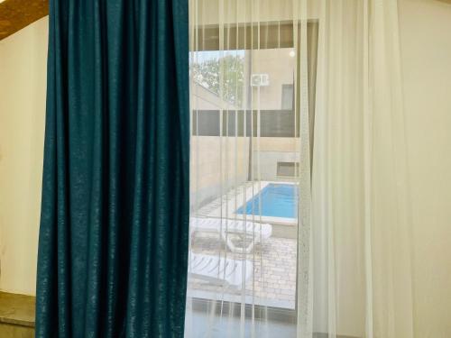 a window with a green curtain and a swimming pool at General guesthouse in Yerevan