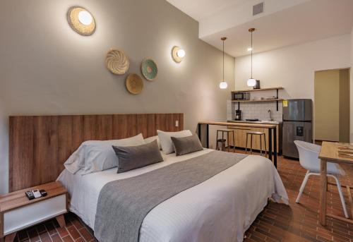 a bedroom with a large bed and a kitchen at The Somos Flats Laureles in Medellín