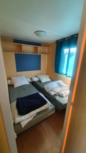 2 Betten in einem kleinen Zimmer mit blauen Vorhängen in der Unterkunft La Maison du bonheur Mobil-home camping 3 étoiles Paris à 45 Km in Saint-Chéron