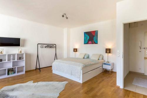 een witte slaapkamer met een bed en een televisie bij Studio Stubenbastei in Wenen