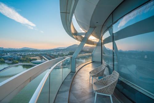 a balcony with two chairs on a building with a view at Sheraton Huzhou Taihu Lake Hot Spring Resort & Spa in Huzhou