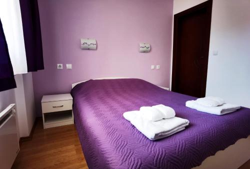 Una cama morada con dos toallas encima. en Апартамент 204 Студенец, en Pamporovo