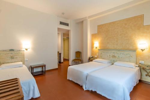 a hotel room with two beds with white sheets at Hotel Machiavelli Palace in Florence