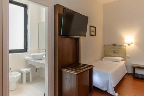 a bedroom with a bed and a bathroom with a flat screen tv at Hotel Machiavelli Palace in Florence