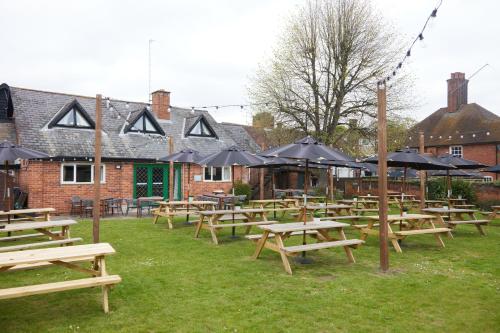 a group of picnic tables with umbrellas in a yard at Bull Hotel by Greene King Inns in Halstead